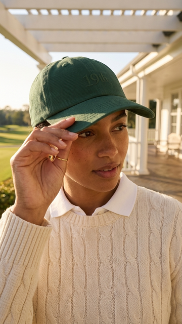 The Hat in heritage green worn at golf clubhouse — womens golf hat lifestyle | Nineteenth Society