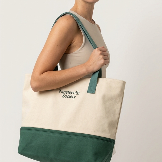 The Round Bag worn on shoulder — ecru canvas tote with forest green cooler base | Nineteenth Society