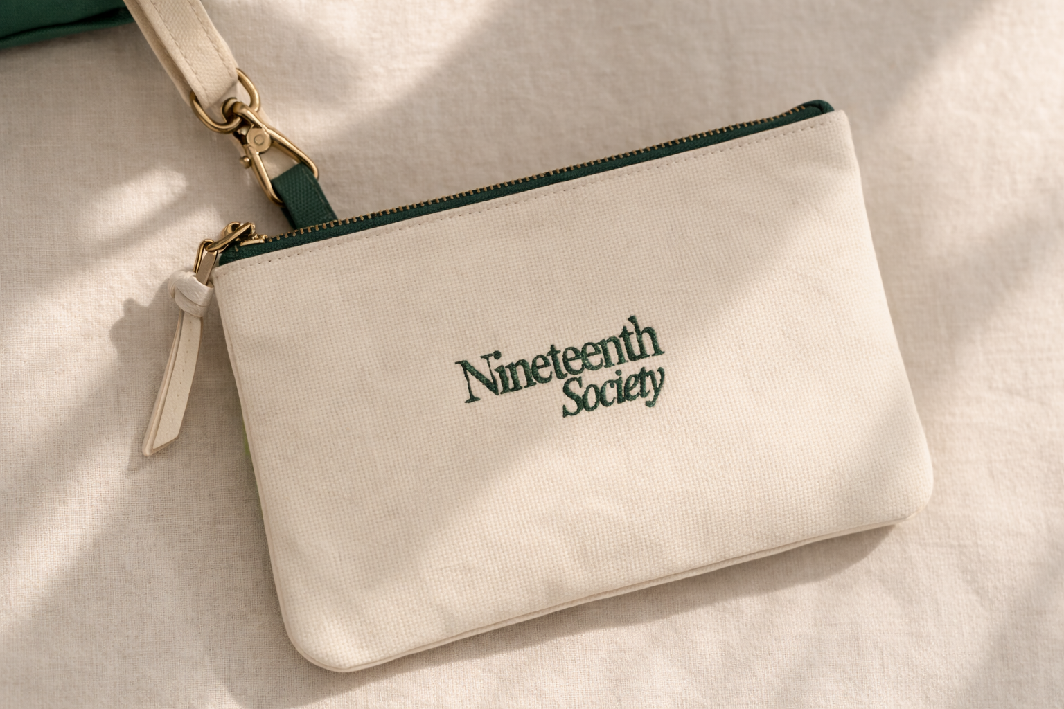 Nineteenth Society branded pouch in ecru canvas with forest green zip — golf accessory | Nineteenth Society
