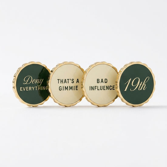 Four ball markers in a row — scalloped gold edge, alternating Heritage Green and cream enamel