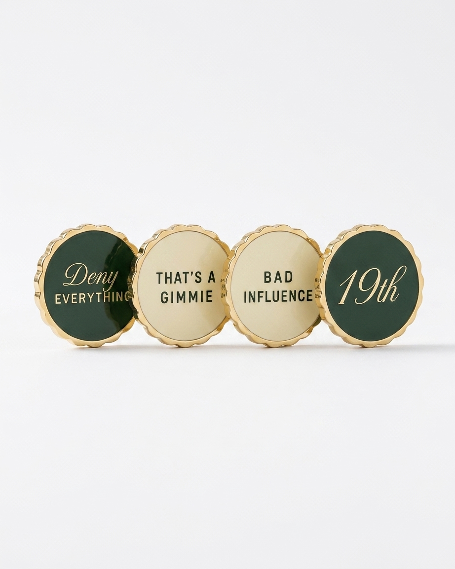 Four ball markers in a row — scalloped gold edge, alternating Heritage Green and cream enamel